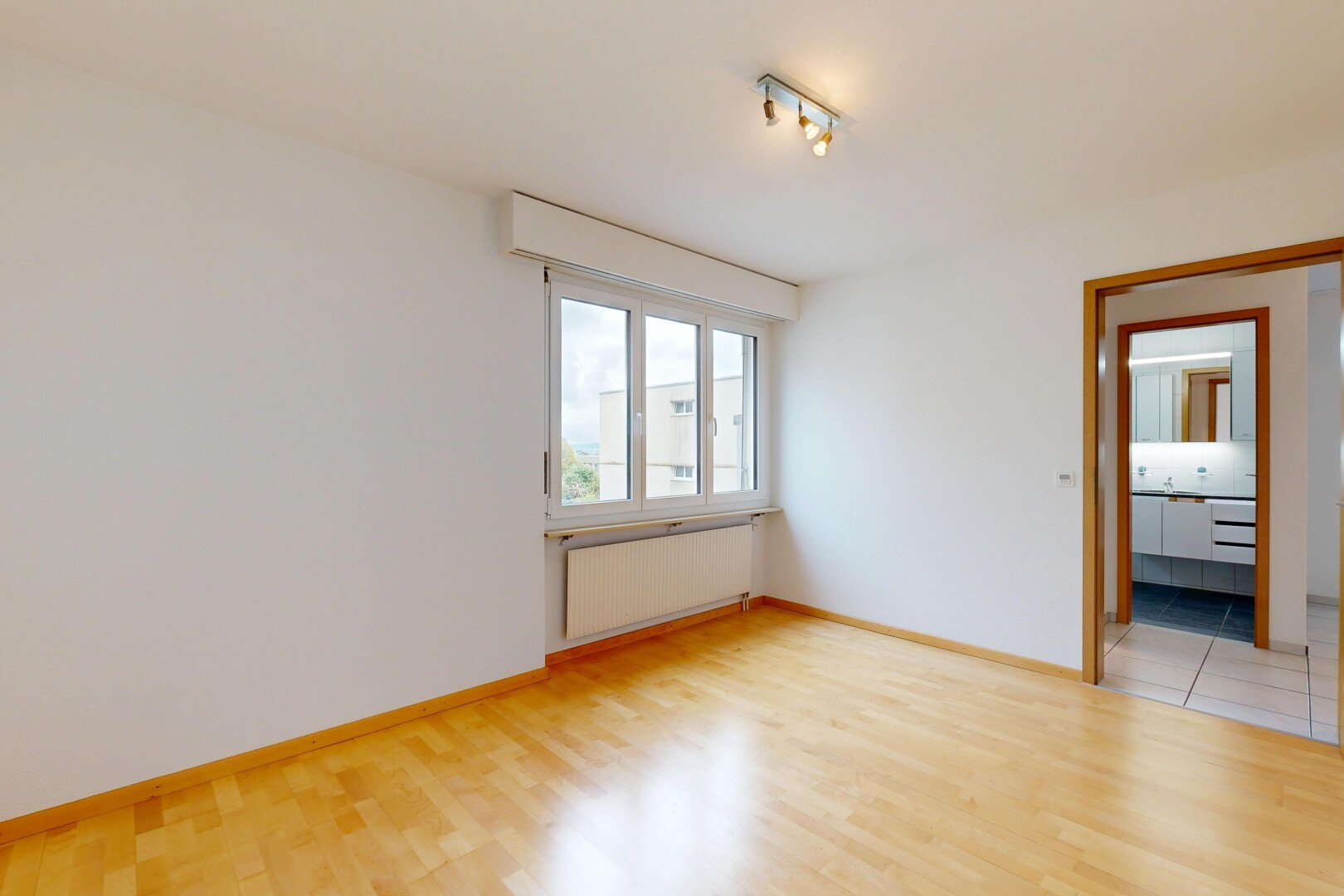 pièce vide avec radiateur, cloison sèche, drywall, éclairage sur rail, et sol en finition bois