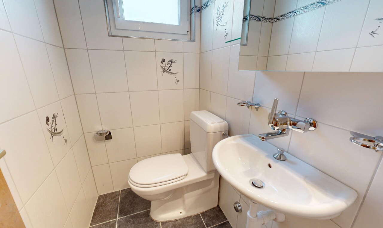 salle de bains avec toilette, évier, mur en carrelage, tile wall, et sol en carrelage