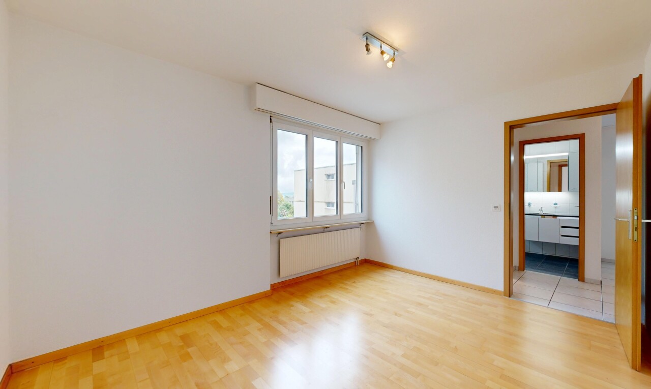pièce vide avec radiateur, cloison sèche, drywall, éclairage sur rail, et sol en finition bois
