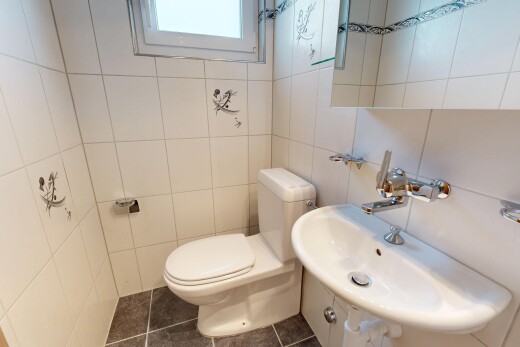 salle de bains avec toilette, évier, mur en carrelage, tile wall, et sol en carrelage