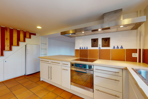 küche mit elektrischer herd, kühlschrank, edelstahlofen, weissen schränken, hellen arbeitsplatten und hellen fliesenböden