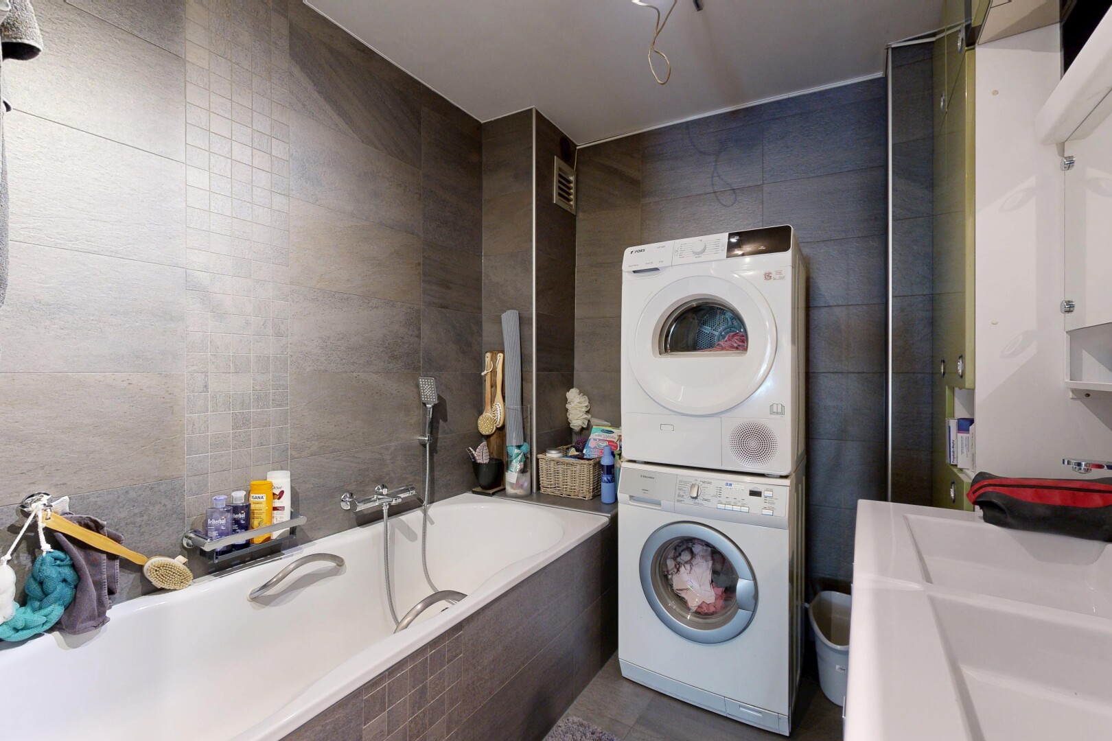 buanderie avec mur en carrelage, tile wall, buanderie, lave-linge et sèche-linge superposés, et inside property