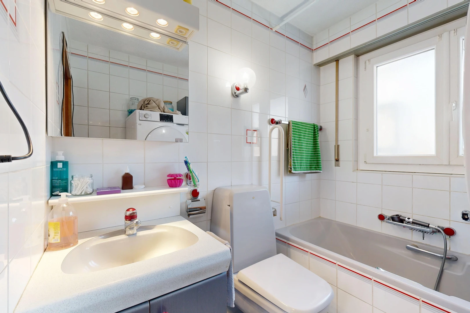 salle de bains avec salle de bain complète, miroir, évier, toilette, et tile wall