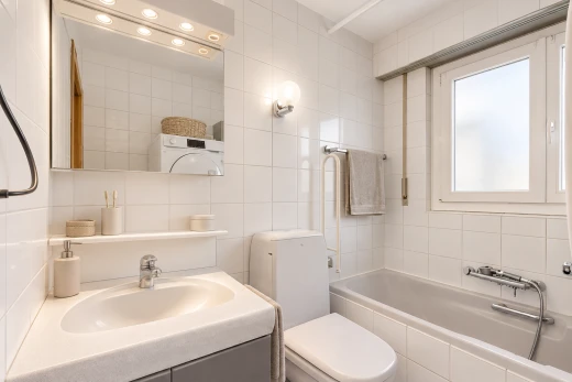 salle de bains avec salle de bain complète, miroir, évier, toilette, et tile wall