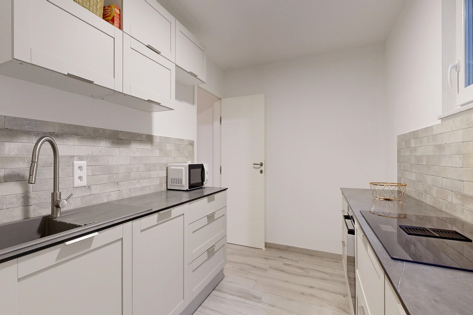 kitchen with tasteful backsplash, white cabinets, light wood-style floors, black electric cooktop, and white microwave