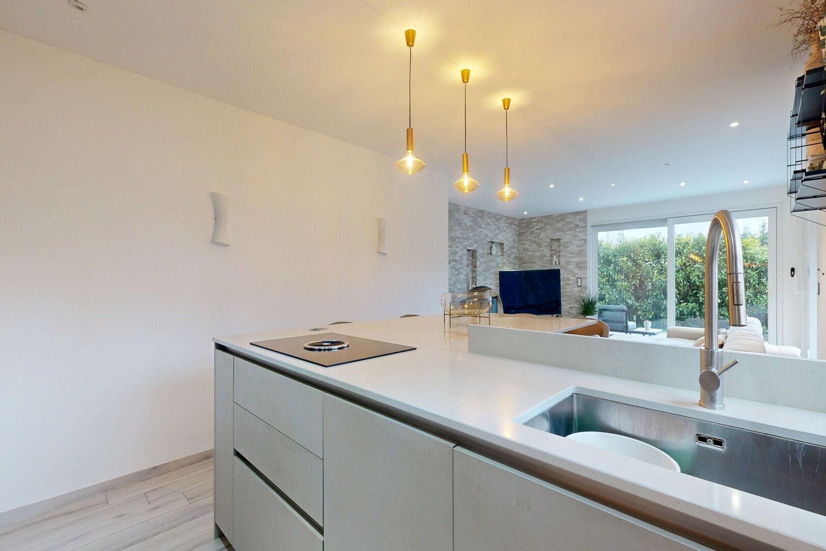 kitchen featuring light countertops, open floor plan, decorative light fixtures, light wood-type flooring, and a stone fireplace