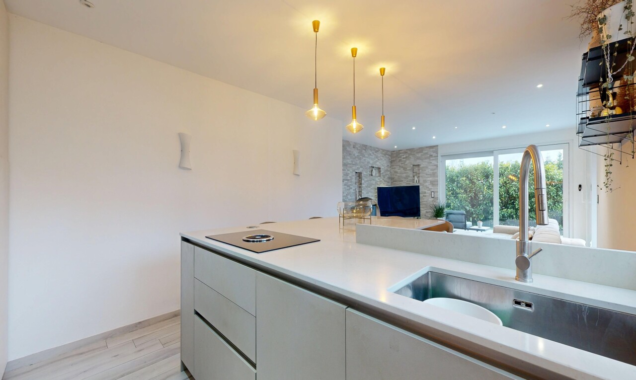 kitchen featuring light countertops, open floor plan, decorative light fixtures, light wood-type flooring, and a stone fireplace