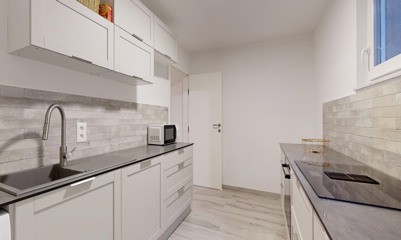 kitchen with tasteful backsplash, white cabinets, light wood-style floors, black electric cooktop, and white microwave