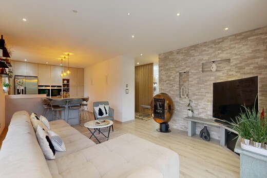 wohn- / esszimmer mit fernseher, holzfußboden, wood finish floor, inside property, und steinwand