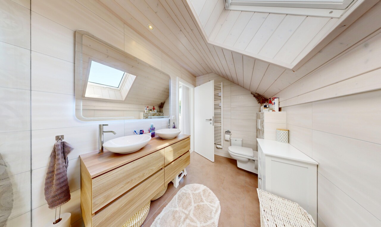 salle de bains avec puits de lumière, vaulted ceiling, plafond voûté, tile wall, et mur en carrelage