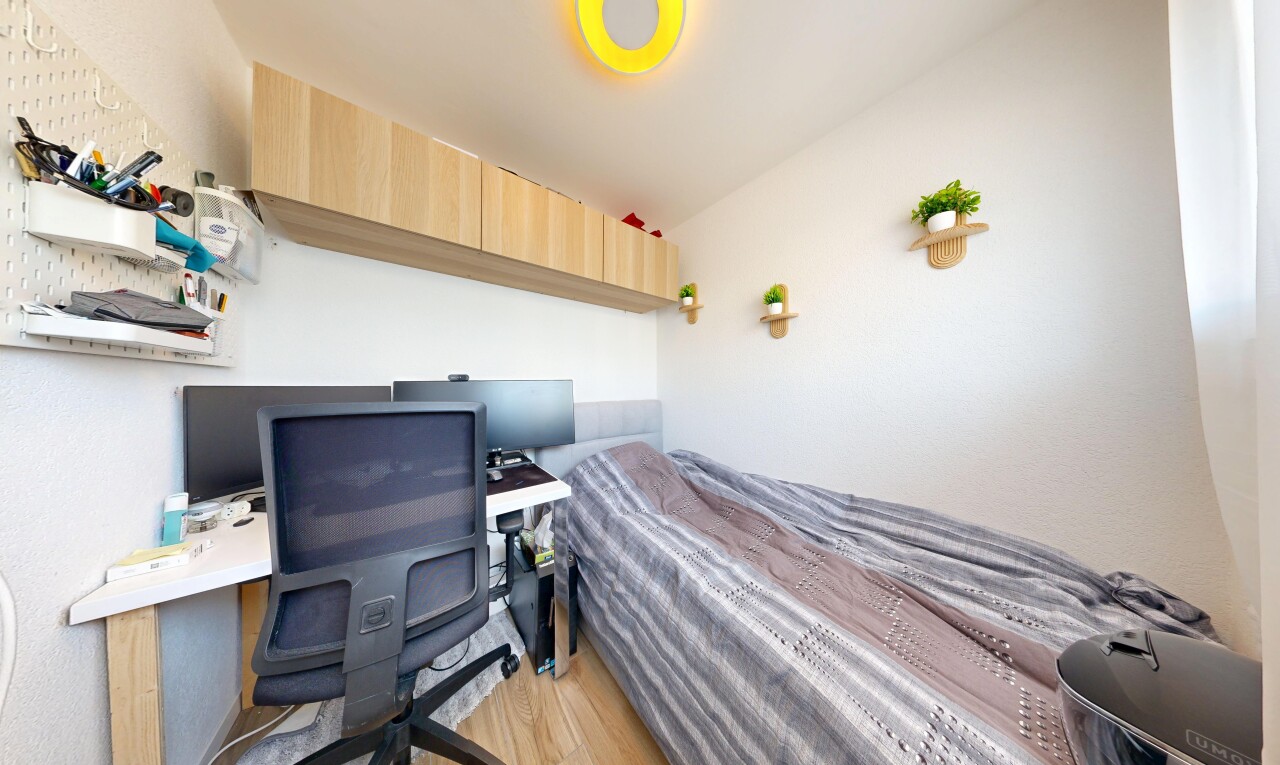 chambre avec espace bureau, télévision, wood finish floor, sol en finition bois, et drywall