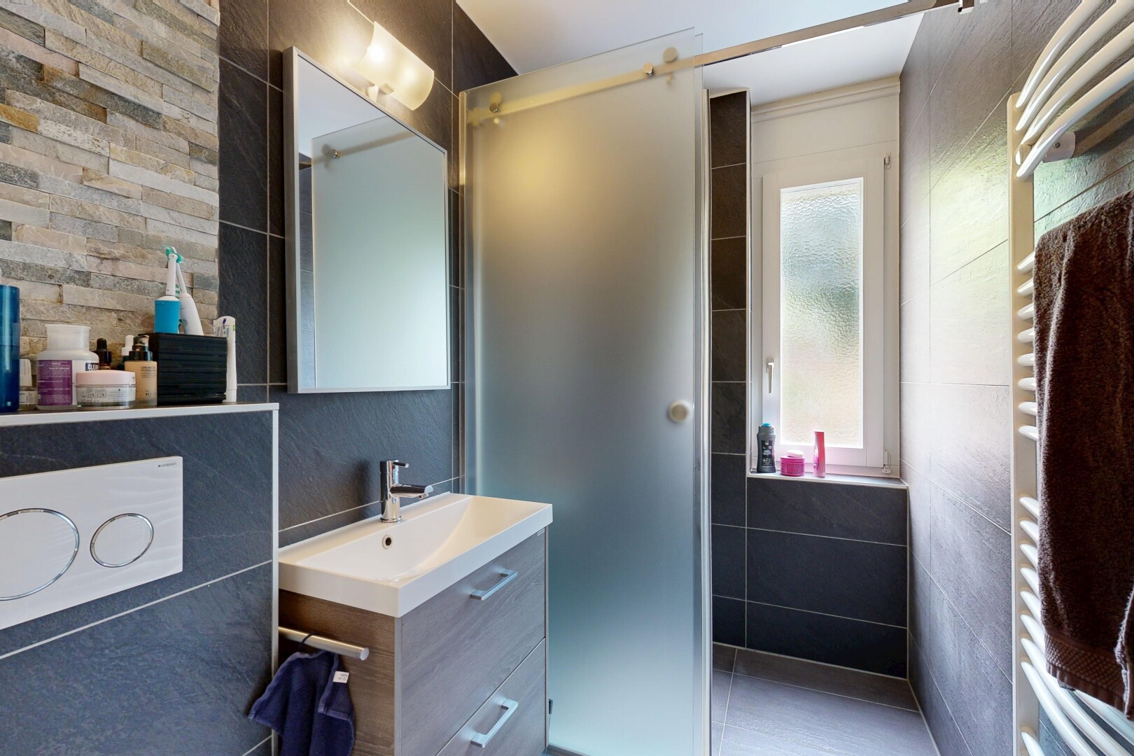 bathroom with a towel warming rack, vanity, and tile walls