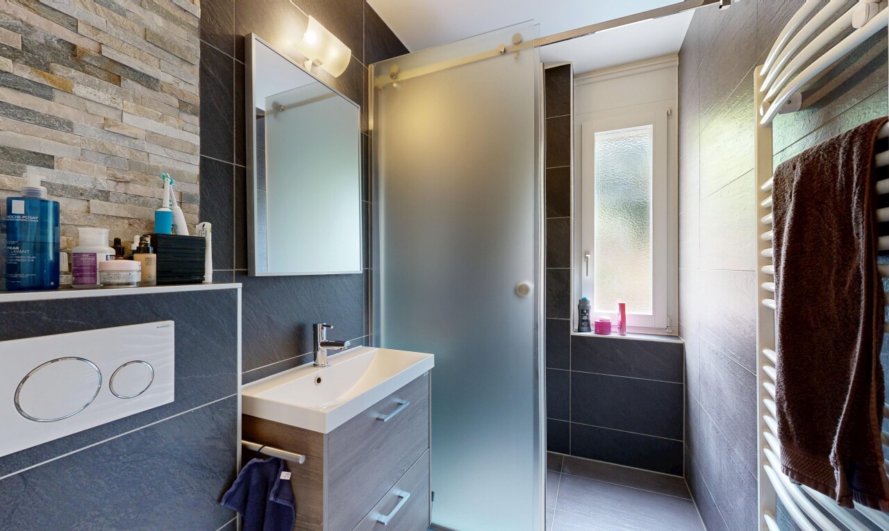 bathroom with a towel warming rack, vanity, and tile walls