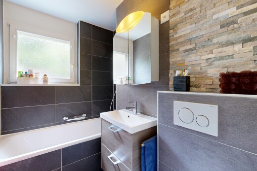 salle de bains avec bain, miroir, salle de bain complète, lavabo (ou coiffeuse selon le contexte), et mur en carrelage