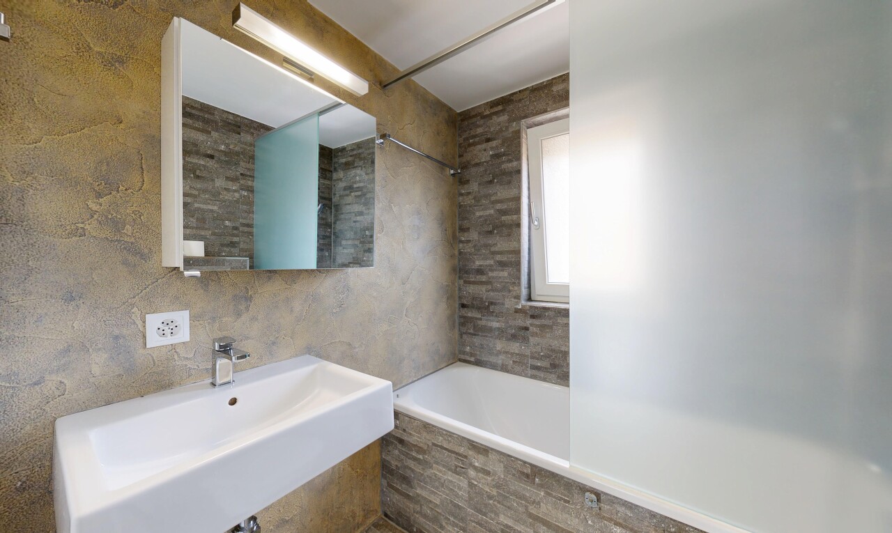 full bathroom featuring tiled shower / bath combo and tile walls