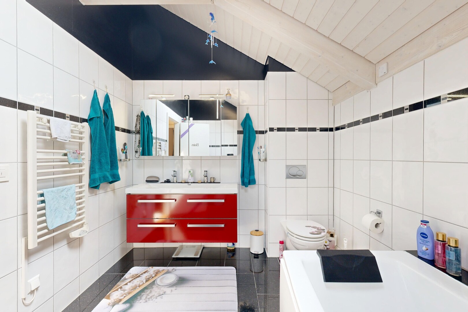 salle de bains avec mur en carrelage, tile wall, plafond à poutres, beamed ceiling, et chauffe-serviettes