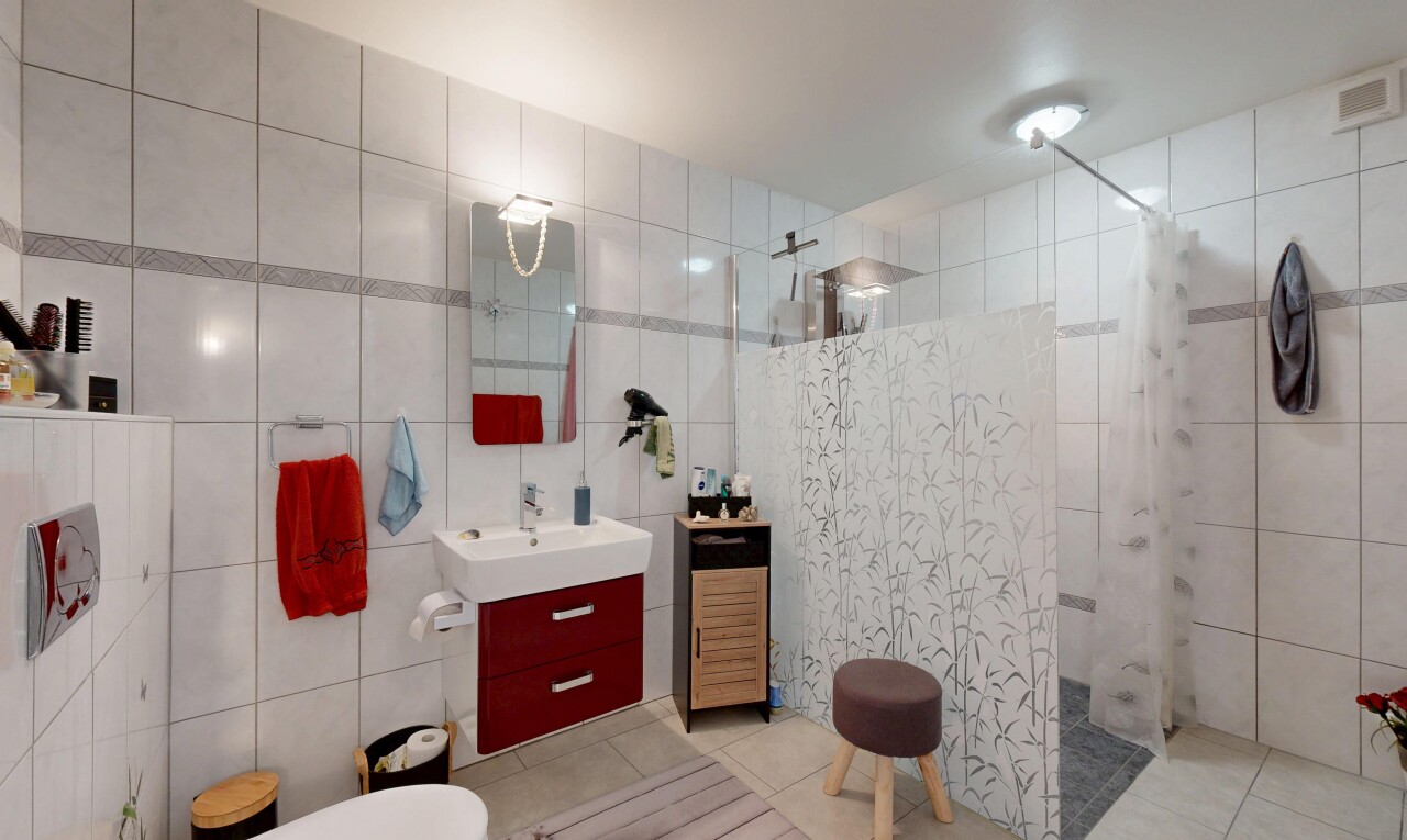 salle de bains avec mur en carrelage, tile wall, lavabo (ou coiffeuse selon le contexte), douche, et sol en carrelage