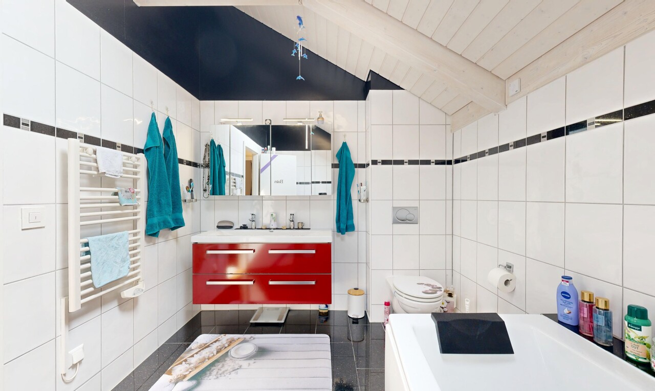 salle de bains avec mur en carrelage, tile wall, plafond à poutres, beamed ceiling, et chauffe-serviettes