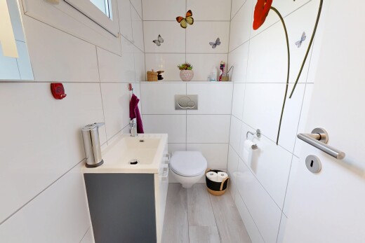 salle de bains avec mur en carrelage, tile wall, lavabo (ou coiffeuse selon le contexte), toilette, et inside property