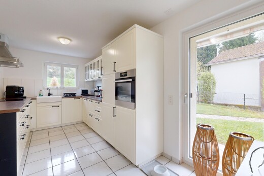 cuisine avec four, light floor, drywall, cloison sèche, et armoires avec insert en verre