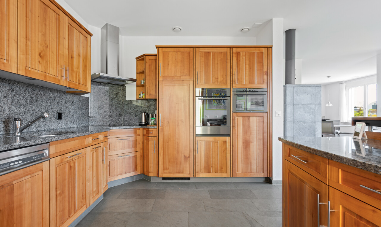 kitchen with dark stone counters, paneled dishwasher, stainless steel oven, decorative backsplash, and wood finish cabinetry