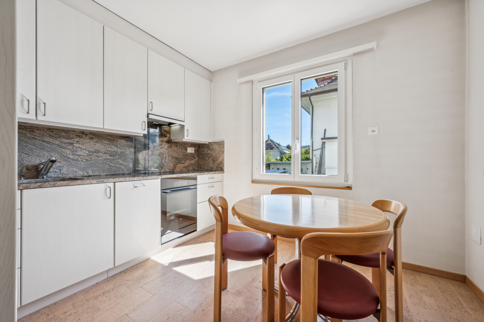 küche mit weiße schränke, white cabinets, light floor, ofen, und dark countertops