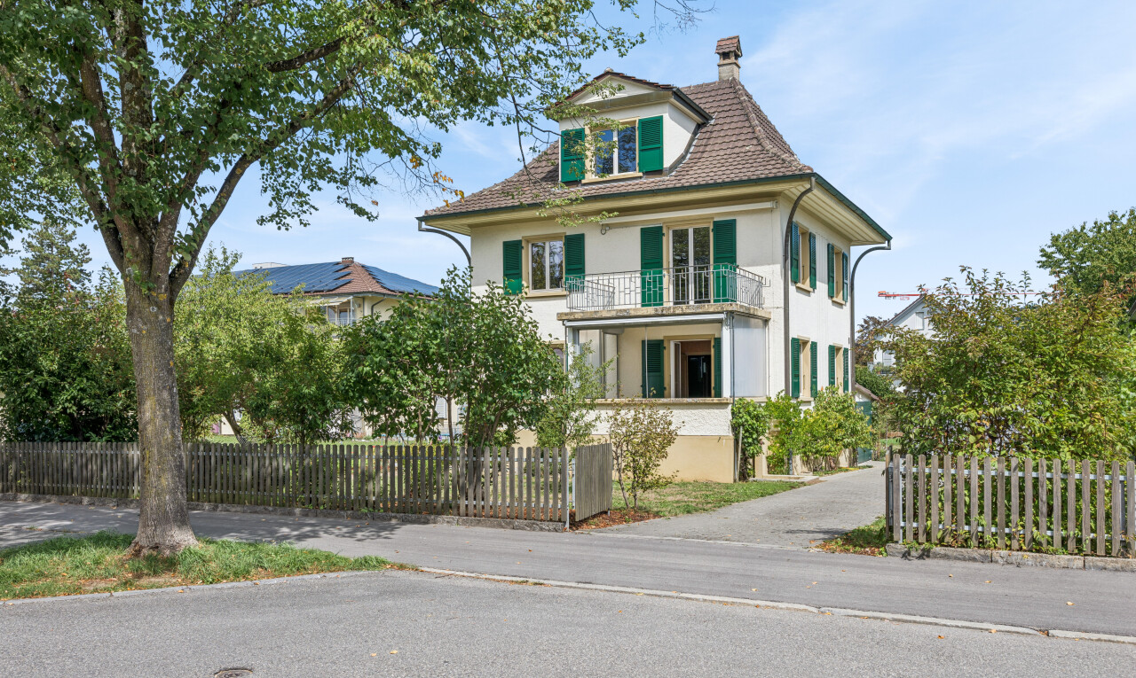 view of home featuring a balcony, a fenced front yard, and a chimney