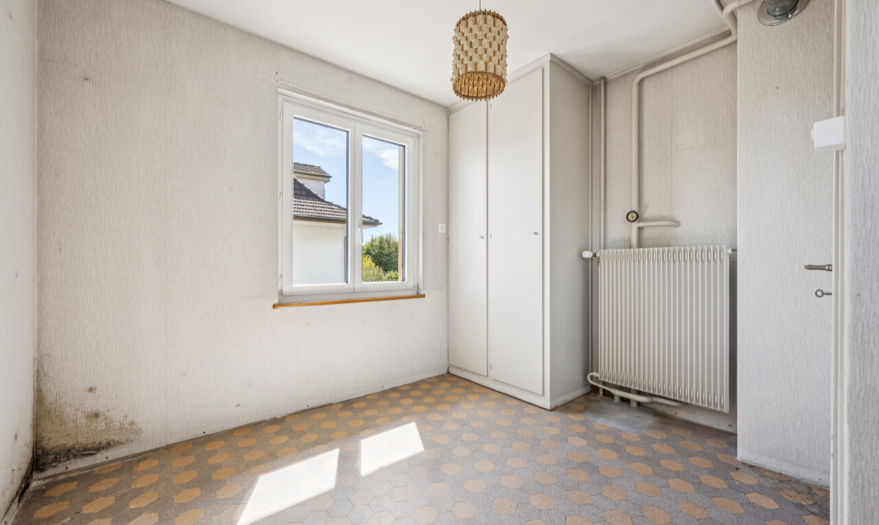 spare room featuring radiator, tile patterned floors, a closet, and pendant lighting