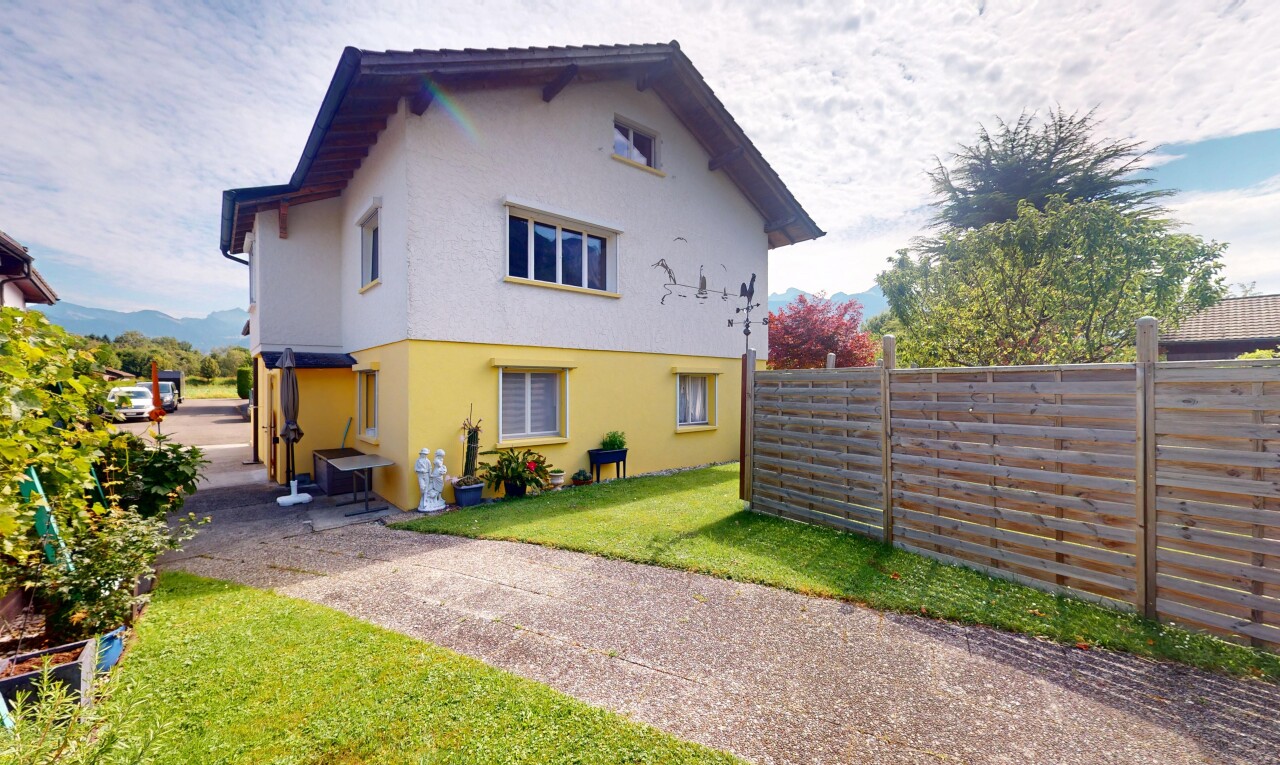 façade avec property visible, clôture, bardage en stuc, pelouse, et day time