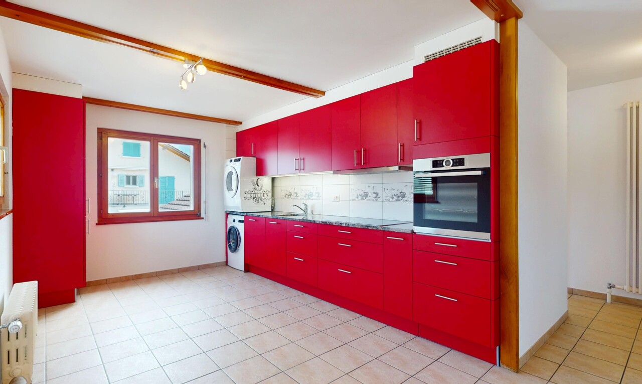 cuisine avec armoires rouges, lave-linge et sèche-linge superposés, backsplash, dosseret, et four