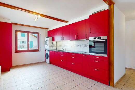 cuisine avec armoires rouges, lave-linge et sèche-linge superposés, backsplash, dosseret, et four