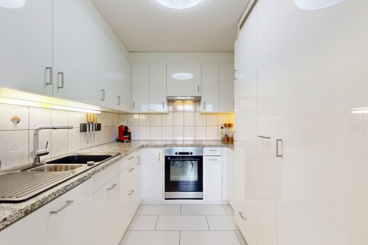 kitchen with stainless steel oven, light stone counters, light tile patterned floors, and white cabinetry