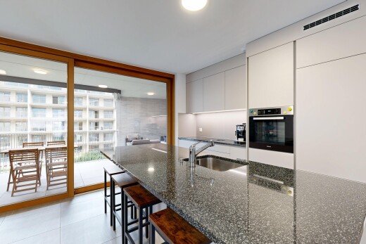 kitchen with modern cabinets, stainless steel oven, a kitchen breakfast bar, access to outside, and dark stone countertops