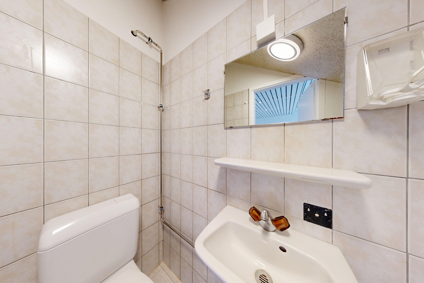 salle de bains avec toilette, tile wall, mur en carrelage, évier, et inside property