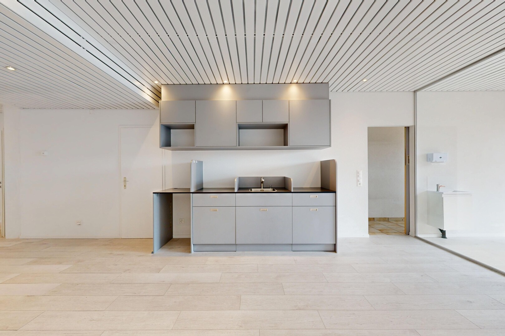 cuisine avec gray cabinets, armoires grises, light floor, drywall, et cloison sèche
