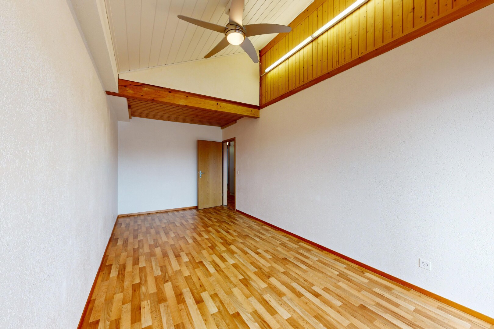 pièce vide avec high ceiling, plafond haut, wood finish floor, sol en finition bois, et vaulted ceiling