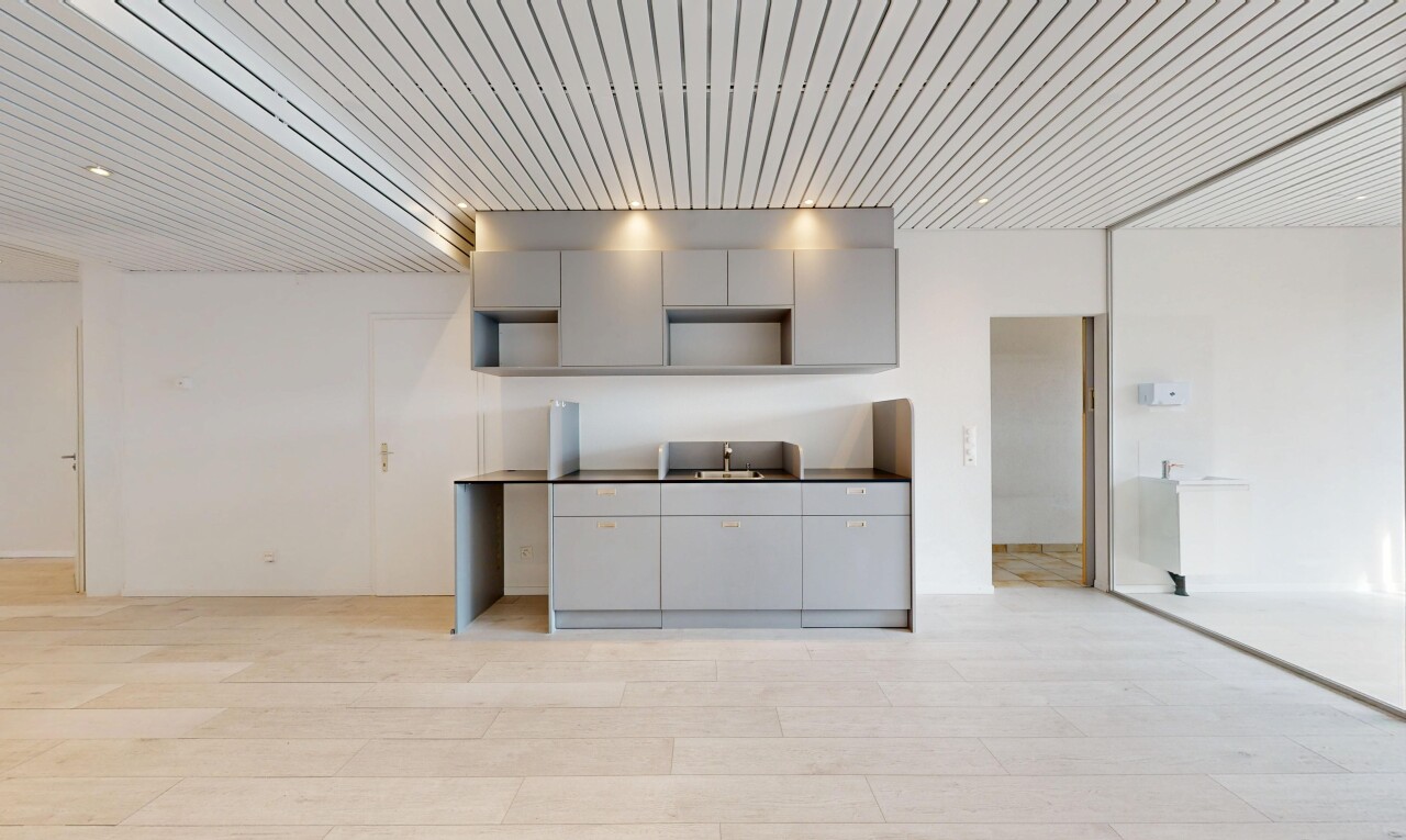 cuisine avec gray cabinets, armoires grises, light floor, drywall, et cloison sèche