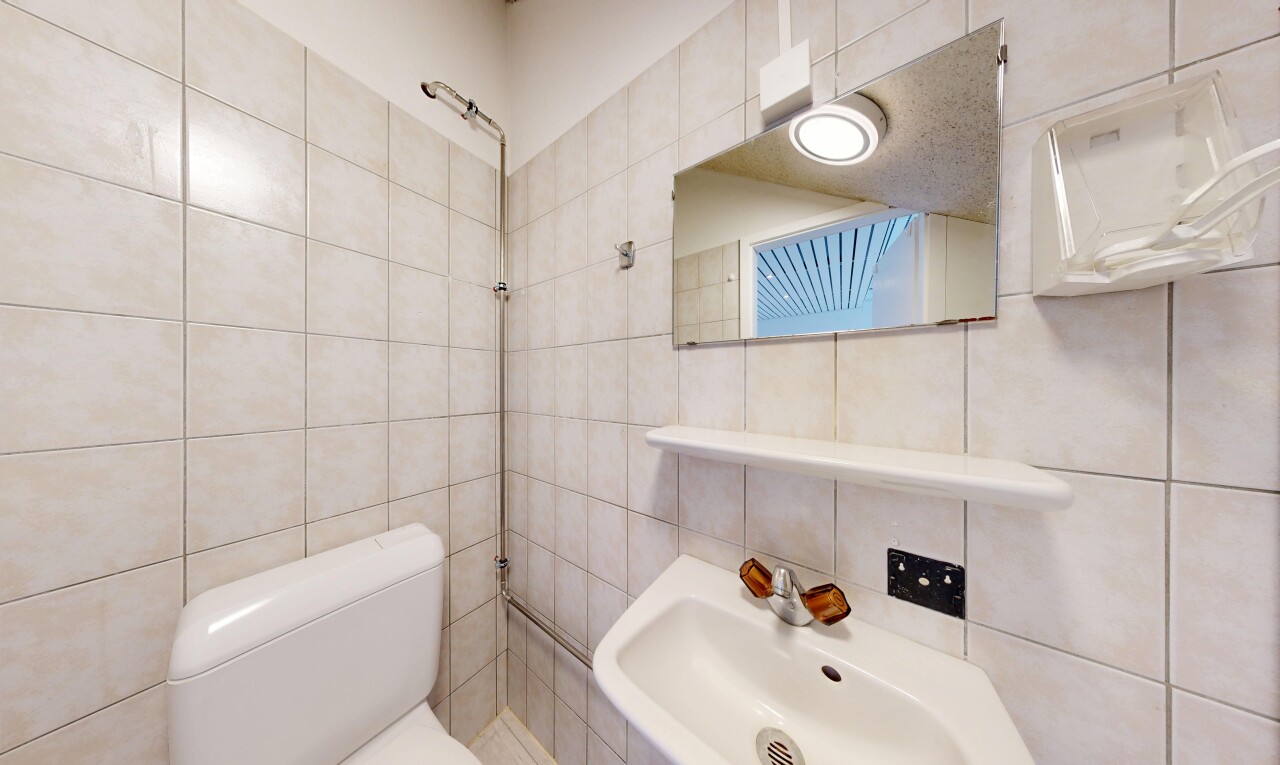 salle de bains avec toilette, tile wall, mur en carrelage, évier, et inside property