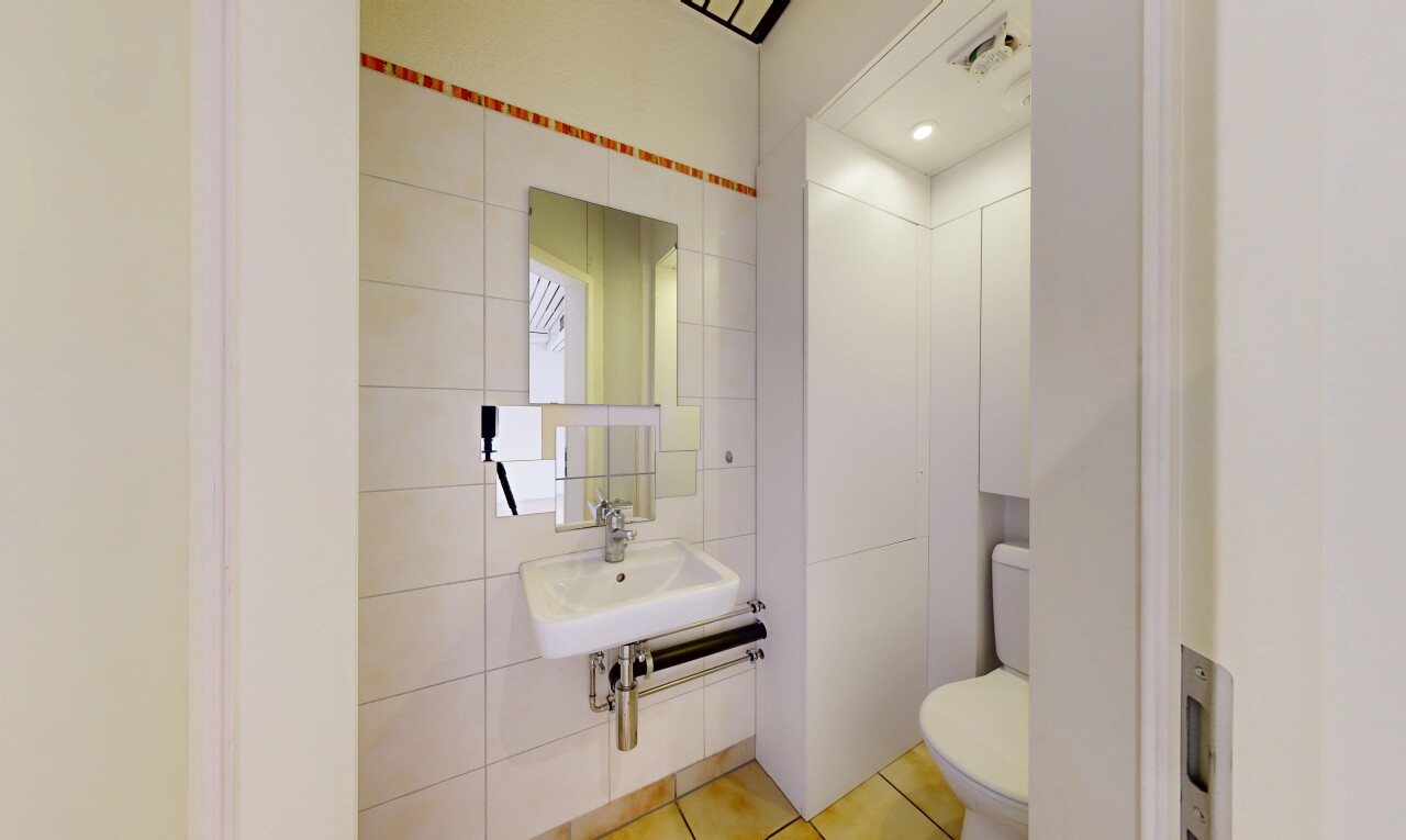 salle de bains avec mur en carrelage, tile wall, miroir, toilette, et éclairage encastré