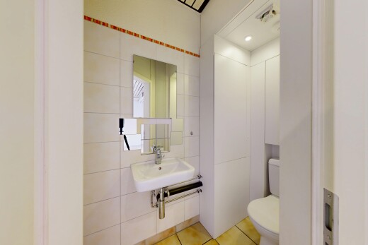 salle de bains avec mur en carrelage, tile wall, miroir, toilette, et éclairage encastré