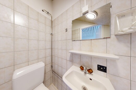 salle de bains avec toilette, tile wall, mur en carrelage, évier, et inside property