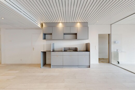 cuisine avec gray cabinets, armoires grises, light floor, drywall, et cloison sèche