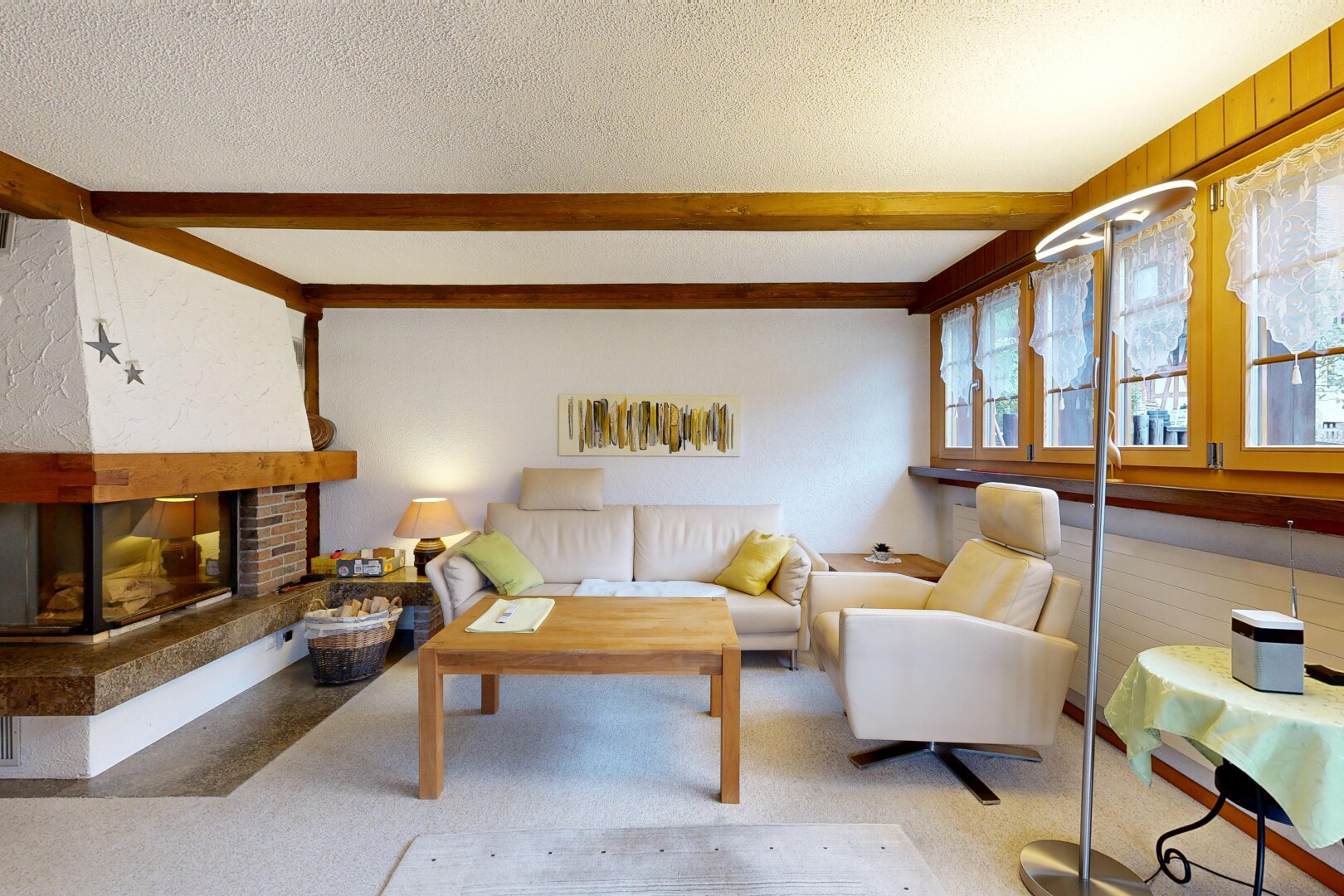 carpeted living area with a brick fireplace, beamed ceiling, and a textured ceiling