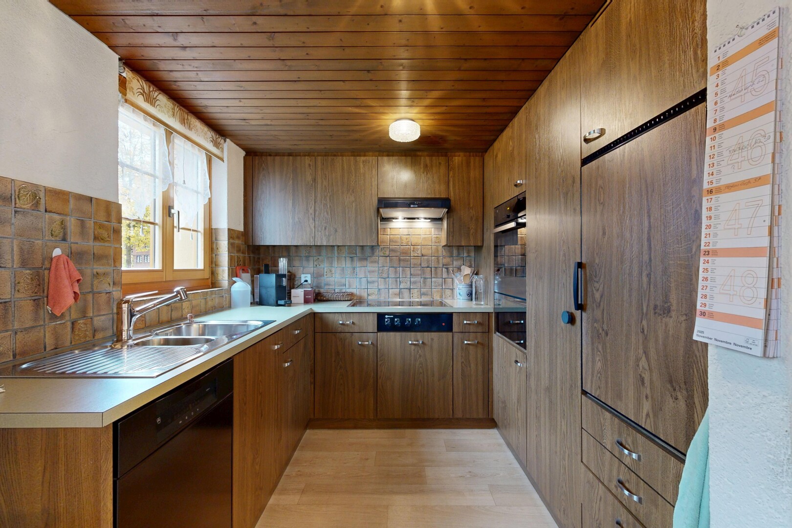 kitchen featuring brown cabinets, black dishwasher, decorative backsplash, light countertops, and wooden ceiling