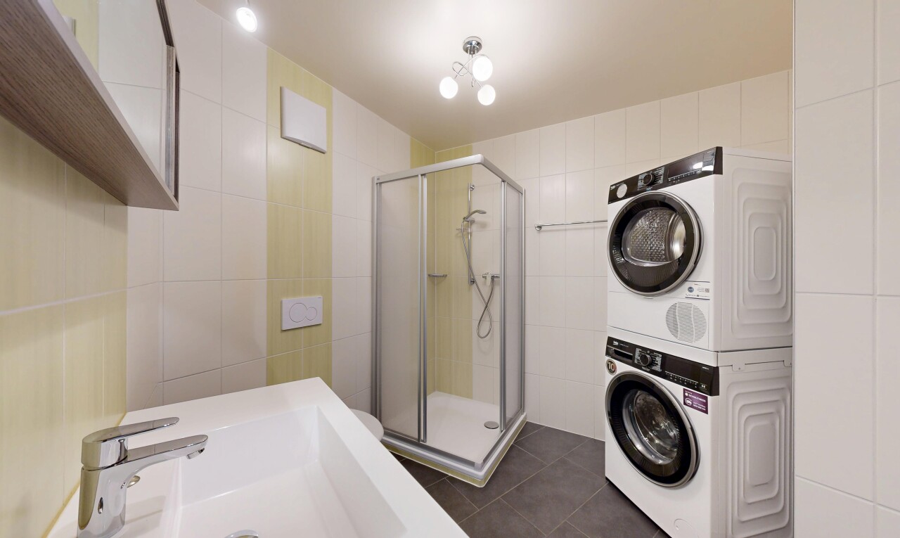 salle de bains avec salle de bain complète, douche, lave-linge et sèche-linge superposés, mur en carrelage, et tile wall