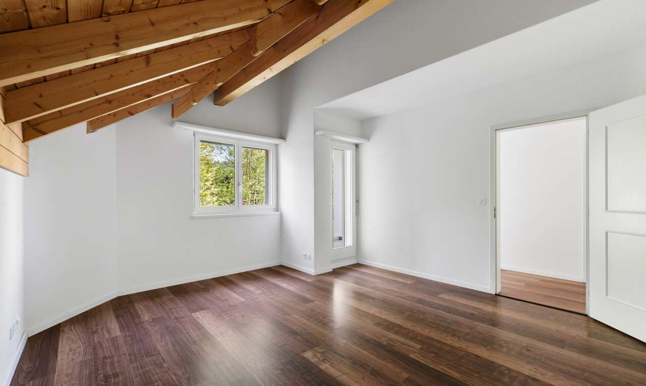 leerer raum mit natürliches licht, balkendecke, gipskartonwand, dachschräge, und holzfußboden