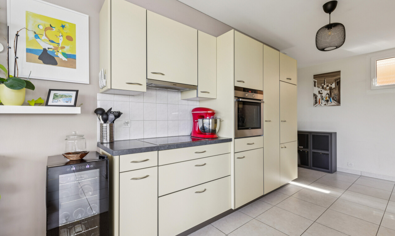 cuisine avec dark countertops, plans de travail, light floor, cream cabinets, et armoires crème