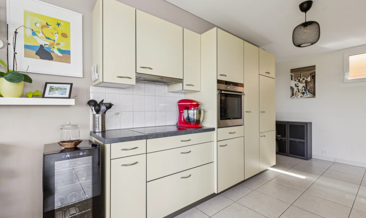 cuisine avec dark countertops, plans de travail, light floor, cream cabinets, et armoires crème