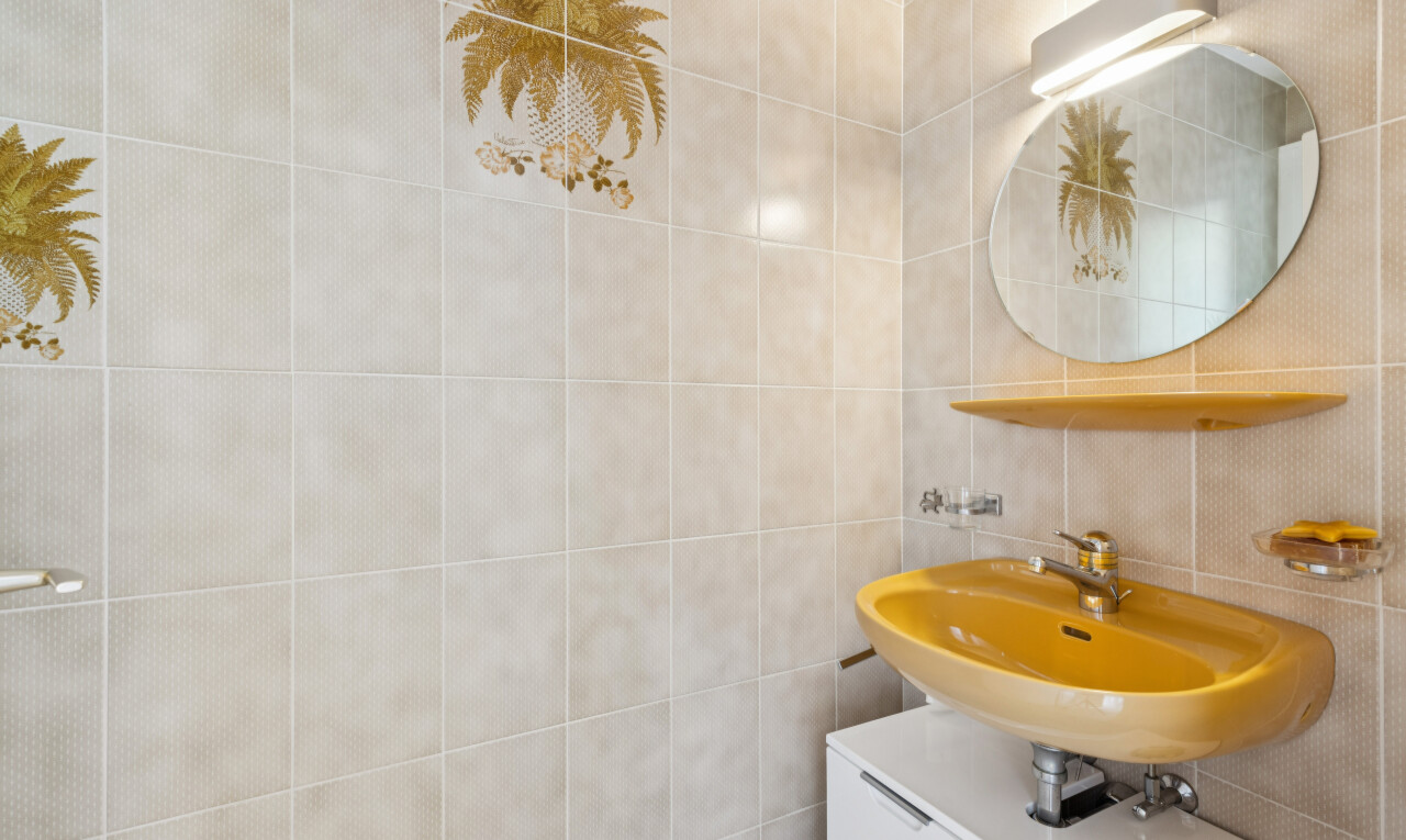 salle de bains avec miroir, évier, mur en carrelage, et tile wall