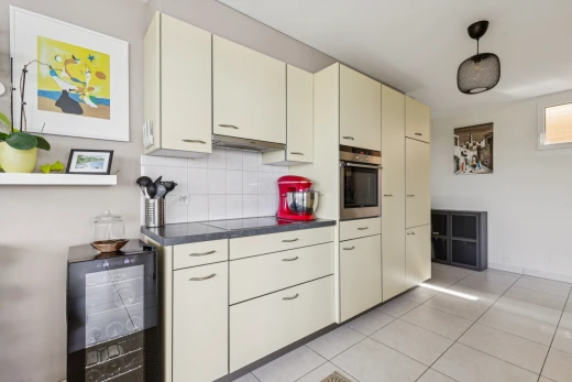 cuisine avec dark countertops, plans de travail, light floor, cream cabinets, et armoires crème